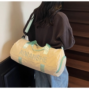 Detail of large beige travel bag with mint green handles shown in a lifestyle setting