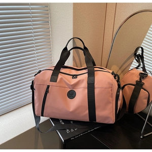 Pink waterproof gym bag with reinforced handles and adjustable shoulder strap on books