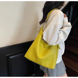 Close-up of bright yellow tote bag in pebble leather worn by model for daily commute