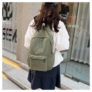 Détail du sac à dos décontracté en nylon vert armée avec logo rond et poches zippées