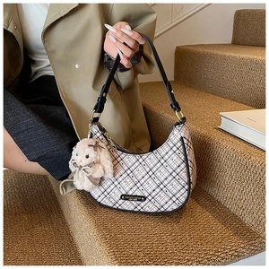 Detail of hobo bag with black and white plaid pattern and plush rabbit charm on stairs