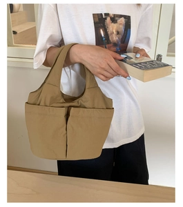 Detail of khaki nylon bucket bag featuring large front pockets for daily commute