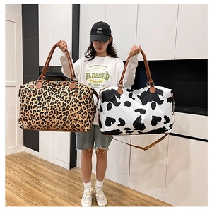 Detail view of large leopard and cow print travel bags with leather handles and straps