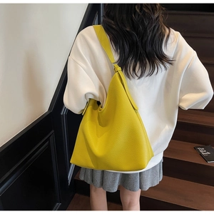 Close-up of yellow pebbled leather hobo bag with a wide strap shown on a model