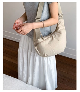Detail of beige crescent crossbody bag with adjustable wide strap and nylon texture