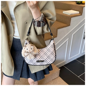 Detail of checkered crescent bag with adjustable strap and plush rabbit charm