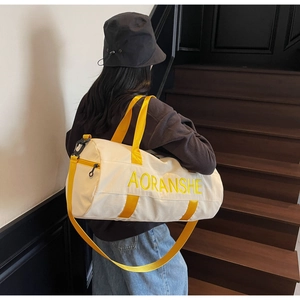 Fashionable travel bag in cream canvas with yellow straps carried on a staircase