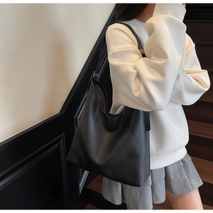 Close-up of a large black pebbled leather hobo tote bag with a minimalist shoulder strap