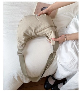 Detail of beige crescent nylon bag with adjustable shoulder strap and logo detail