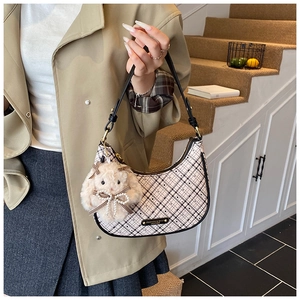Detail of crescent shoulder bag featuring beige checkered fabric and plush rabbit charm