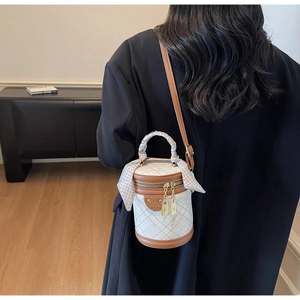 Detailed back view of a white checkered bucket bag with brown leather trim and silk scarf handle