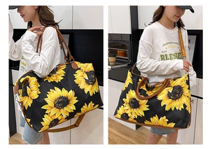 Detail of large sunflower print travel bag showing adjustable shoulder strap and leather handles