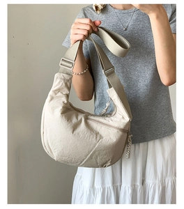 Detail of cream crescent crossbody bag showing textured nylon fabric and shoulder strap