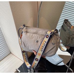 Detail of light grey nylon crossbody bag with chic embroidered wide strap and metal logo