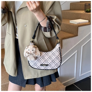 Detailed view of hobo crescent bag in pink plaid with a plush rabbit charm and shoulder strap