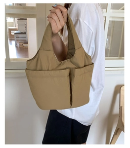Detail of khaki nylon bucket tote bag with two functional front pockets and sturdy handles