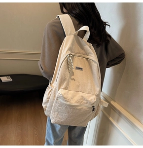 Rear view of a model wearing a beige canvas backpack with a large main compartment