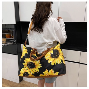 Detail of large sunflower print travel bag with brown leather handles and yellow strap