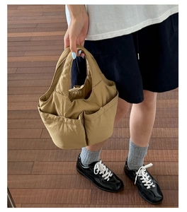Detail of khaki nylon tote bag featuring multiple deep pockets for daily commute