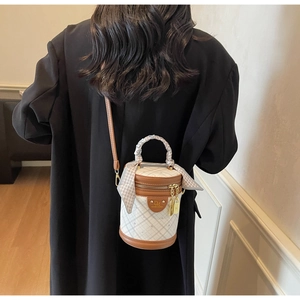 Rear view of a chic plaid bucket bag with silk scarf handle and leather trim strap