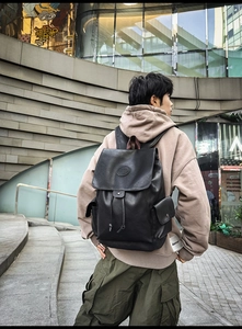 Detail of black leather cargo backpack with flap closure and side utility pockets