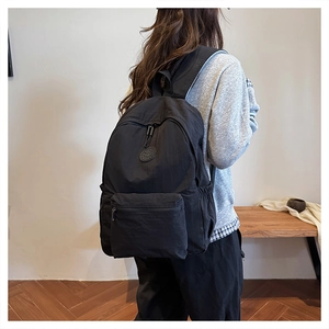 Vue latérale d'un sac à dos noir en nylon porté par un mannequin dans une pièce
