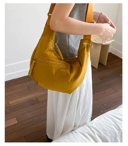 Detail of yellow nylon crescent tote bag with wide strap and metallic buckle adjustment