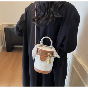 Close-up of white bucket bag with lattice pattern and silk scarf handle detail