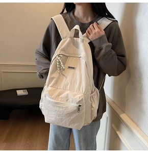 Close-up of lightweight beige nylon backpack worn by a model in a minimalist urban setting