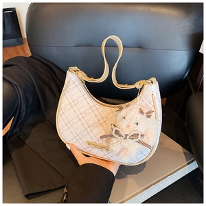 Detail of white checkered crescent bag with plush bunny charm and golden logo plate
