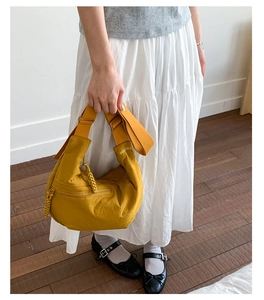 Detailed shot of yellow crescent bag with adjustable shoulder strap and embroidery