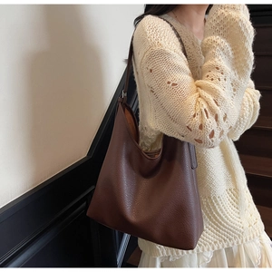 Close-up of deep brown lychee-textured leather Hobo bag worn by model on a beige sweater