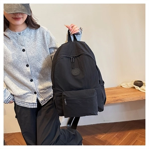 Détail d'un sac à dos noir en nylon avec logo SPORT porté à la main par un mannequin