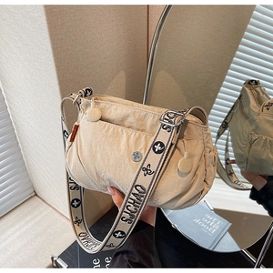 Detail of beige nylon crossbody bag featuring wide jacquard strap and zip pocket texture