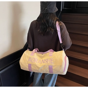 Macro detail of beige travel duffel with purple straps and embroidery on wooden stairs