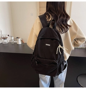 Detail of minimalist black canvas backpack with woven zipper pulls and side pockets
