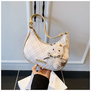 Detail view of beige plaid crescent bag with leather trim and plush rabbit charm