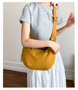 Detailed view of yellow nylon dumpling bag featuring wide strap and front zipper pocket