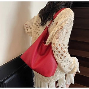Detailed view of red lychee texture shoulder bag showing side drawstring on a model