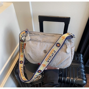Detail of light grey nylon crossbody bag featuring stylish patterned strap and multi-zippers