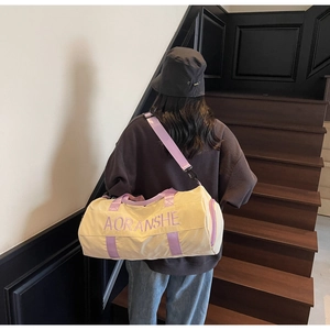 Outdoor view of a cream and purple travel duffel bag shown on a model on stairs