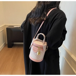 Pink quilted bucket bag detail with floral scarf handle and gold hardware on dark coat