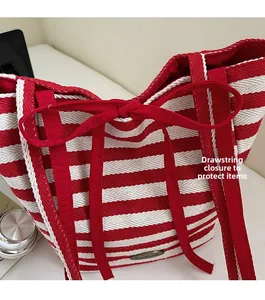 Detail of red and white striped tote bag showing drawstring closure and handmade metal tag