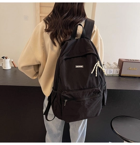 Rear view of black canvas backpack showing adjustable straps and side pocket detail