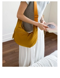 Detail of mustard yellow crescent bag with front zipper pocket and woven rope puller