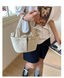 Detail shot of the beige minimalist tote bag featuring dual front utility pockets