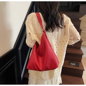 Close-up of a large red lychee grain leather hobo bag on a model's shoulder for commute