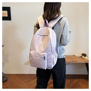 Vue arrière d'un sac à dos en nylon violet clair porté par un mannequin au quotidien