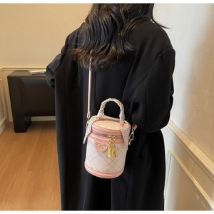 Detailed side view of pink plaid bucket bag with silk scarf wrapped handle on a model