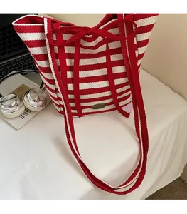 Detail of red and white striped canvas tote bag with handmade badge and bow decoration